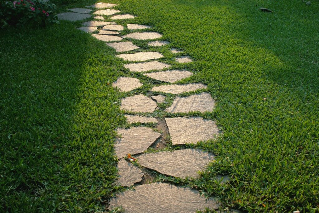 Caminho de pedras naturais em jardim, ilustrando uso de quartzito e ardósia para decoração e delimitação de espaços verdes.
